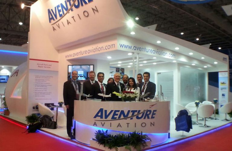 People pose in front of the Aventure Aviation booth at the 2015 Dubai Airshow