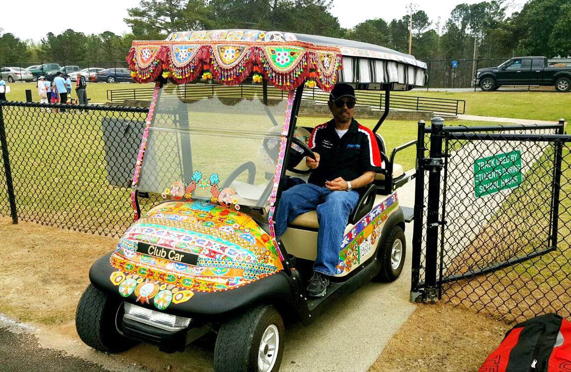 Aventure Aviation President Zaheer Faruqi drives a golf cart to transport cricket spectators