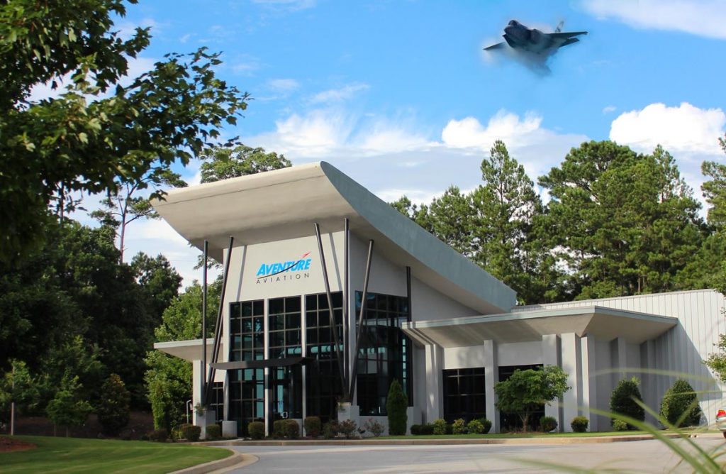 Aventure Aviation's headquarters, with an F-35 fighter jet apearing above it over a blue sky.