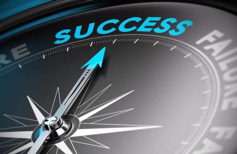 Close up of a compass pointing to the word "success" at the top of the compass.