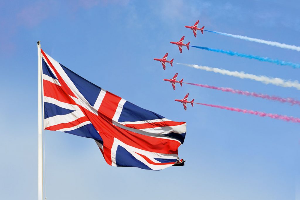 Fighter planes in formation high in the sky, above a large British flag