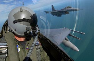 An F-16 fighter pilot in flight watches his wingman from his cockpit