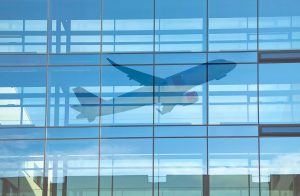 Airplane taking off from airport, reflected in large terminal window