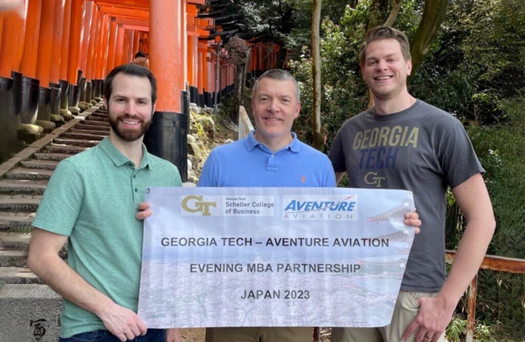 Three American men in Japan holding a banner saying "Georgia Tech Aventure Aviation Evening MBA Partnership Japan 2023"