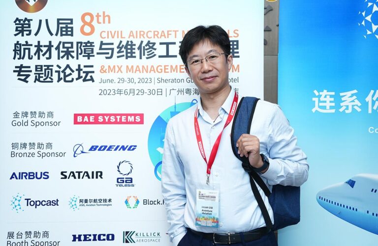 Chinese man standing in front of a sign with Chinese writing at an aviation tradeshow