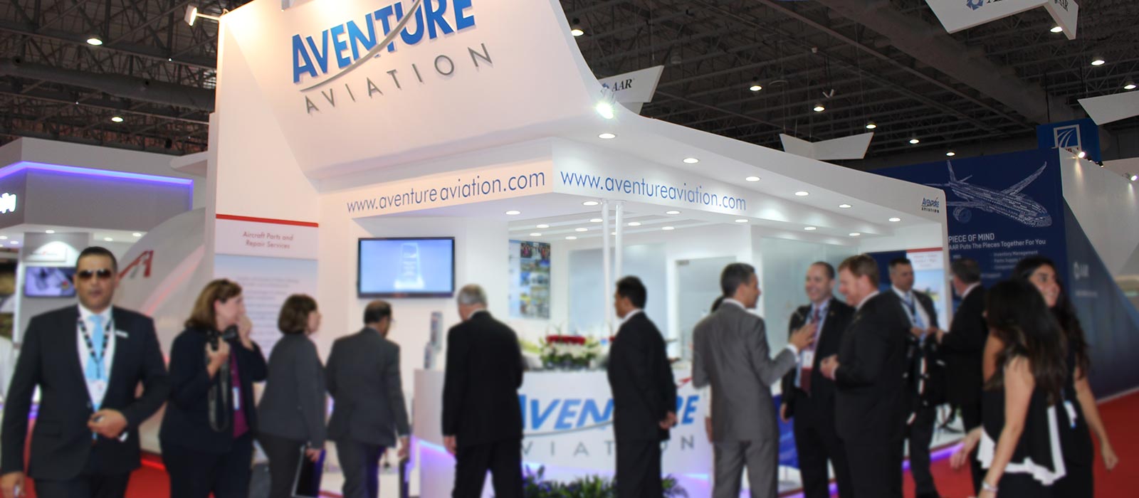 A large tradeshow booth saying "Aventure Aviation" at the top, with over a dozen people outside