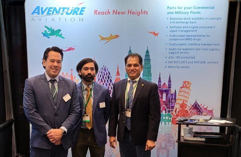 Three men stand in front of a trade show booth stand that says Aventure Aviation