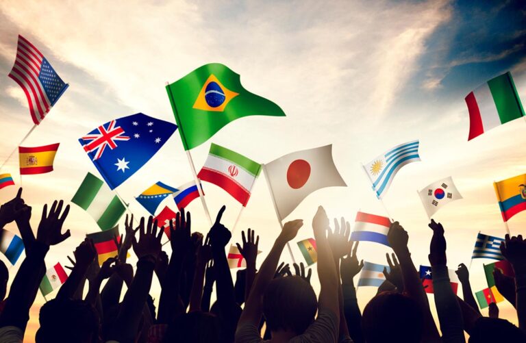Over a dozen hands in sillouette each holding a national flag competing in the World Cup