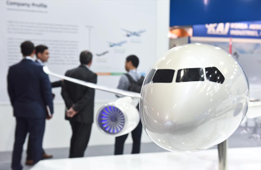 Attendees in a trade show booth with a large airplane model