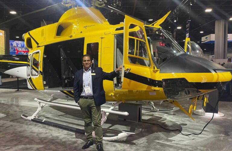 Man stands in front of a static display helicopter inside a trade show hall
