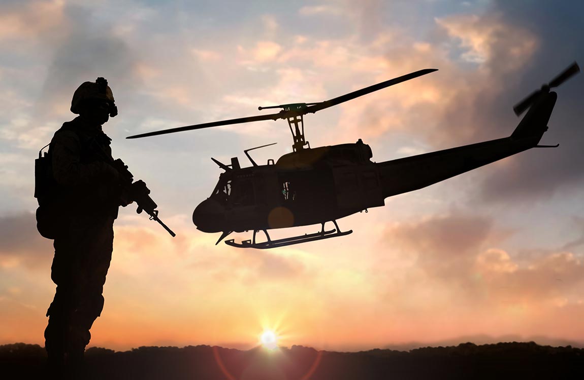 A soldier looks at a military helicopter in flight