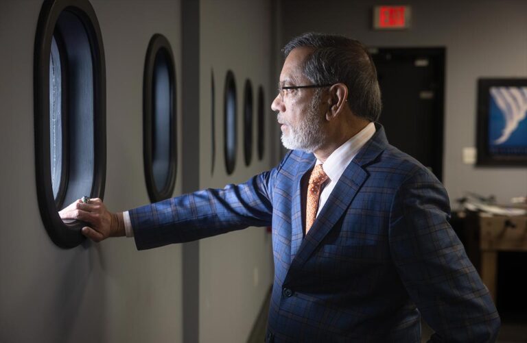 A man in an office looks out a window that resembles an airplane window
