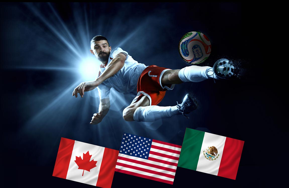 A soccer player in a stadium at night in front of a spotlight, kicks a ball in the air above the flags of Canada, USA, and Mexico
